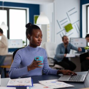 African businesswoman holding cup of coffie reading project briefing