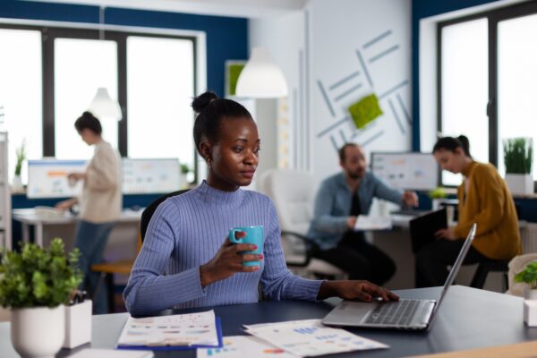 African businesswoman holding cup of coffie reading project briefing